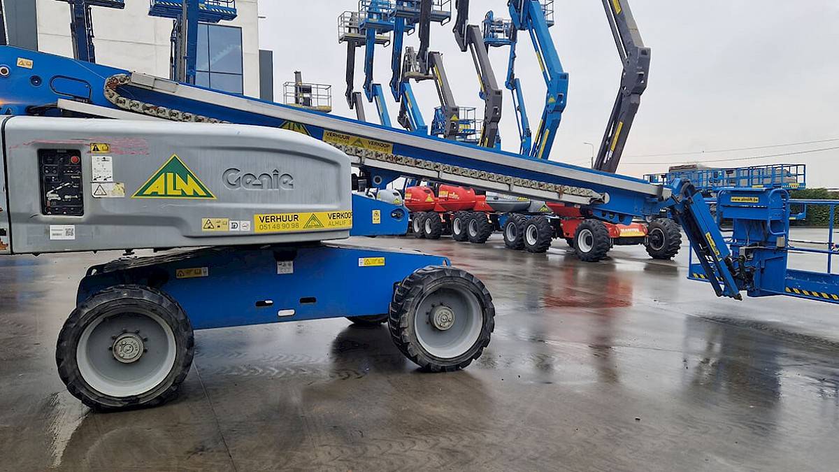 Le côté d'un élévateur à nacelle Genie S-65 4WD bleu avec cage, qui ressemble à un jeune élévateur à nacelle d'occasion.